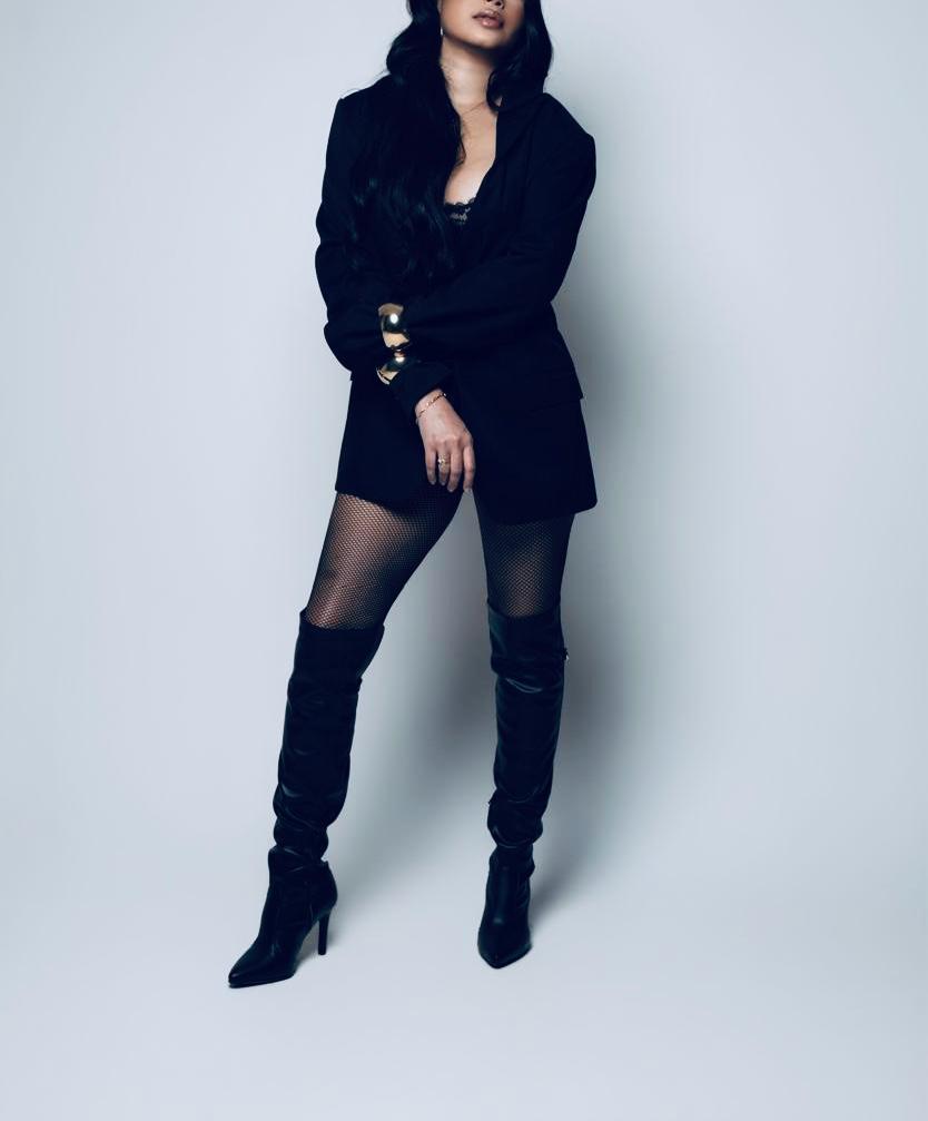 Retrato editorial de mulher usando blazer preto e botas altas